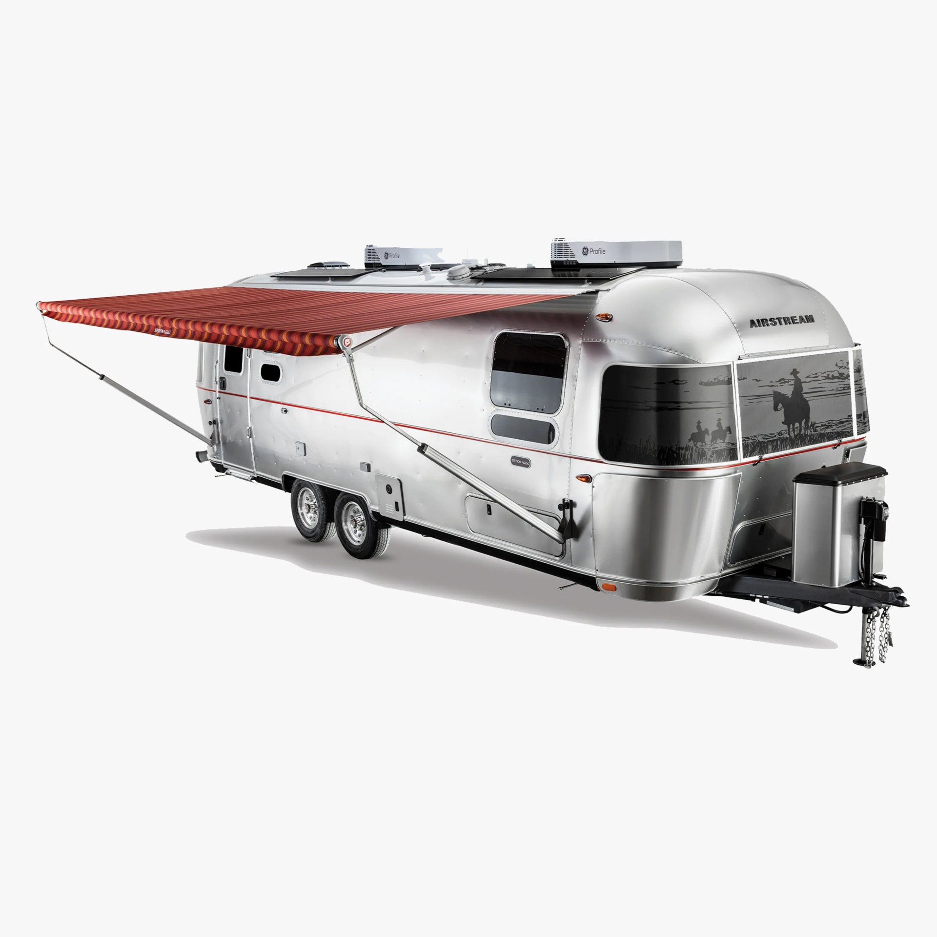 Silver Airstream travel trailer with red striped awning extended and cowboy silhouette window decal.
