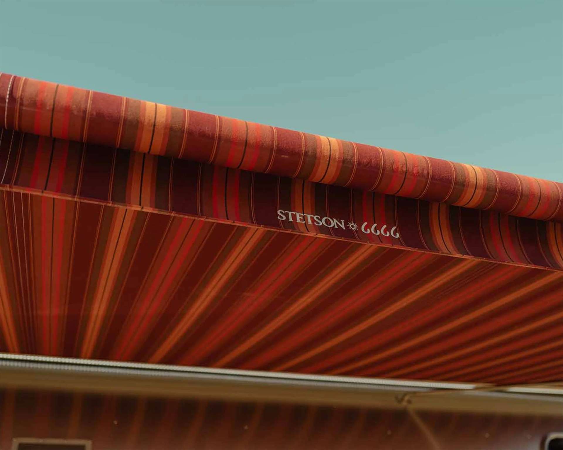 Red and orange striped fabric awning with "STETSON" logo against a clear blue sky.