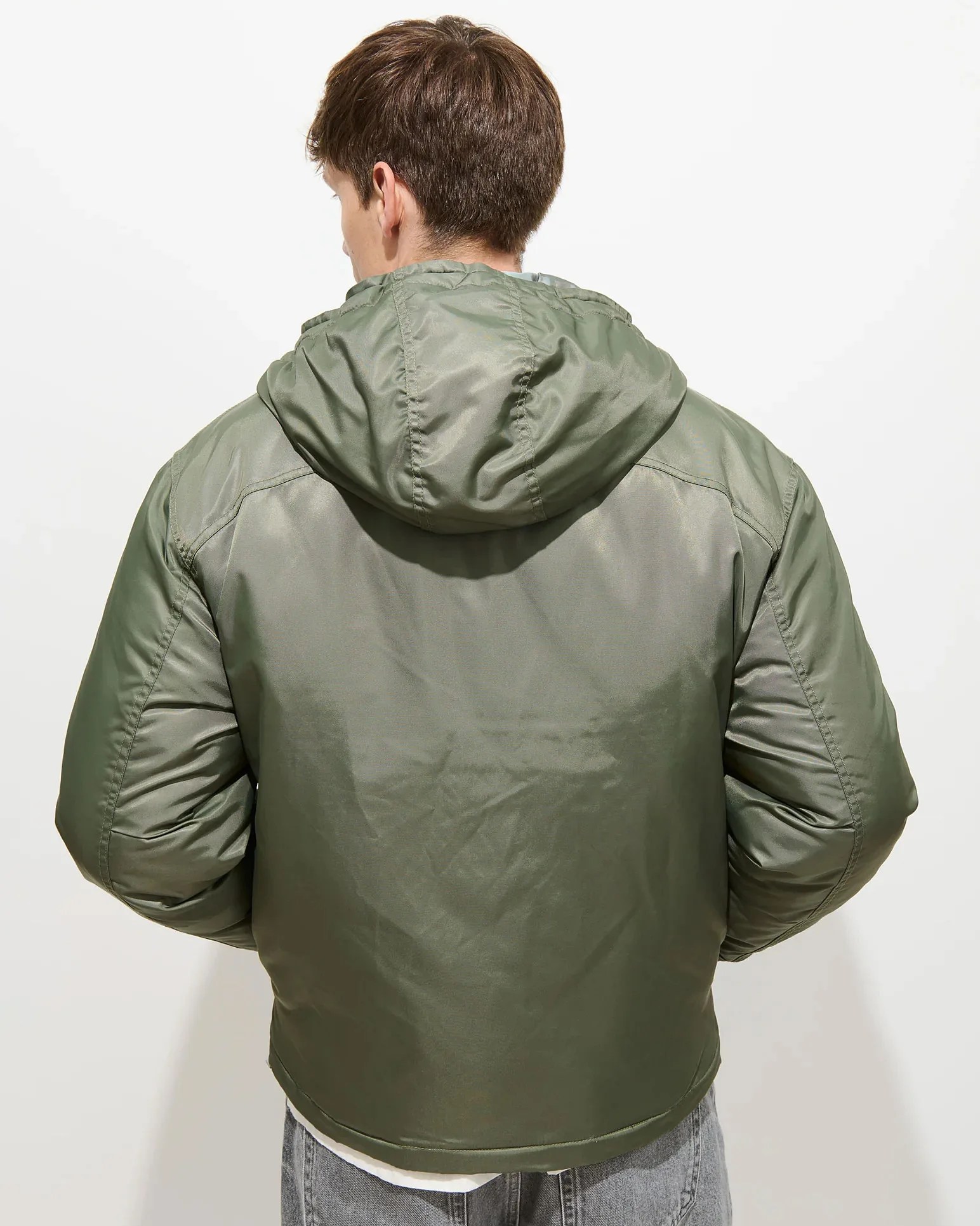Olive green hooded puffer jacket with a smooth, slightly shiny finish worn by a person facing away.