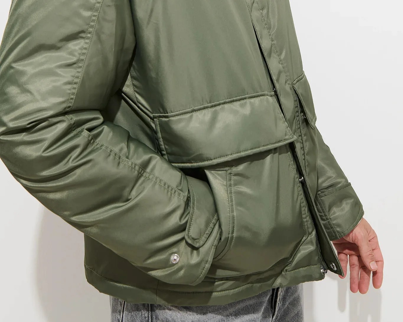 Olive green padded jacket with snap-button cuffs and flap pockets worn by a person.