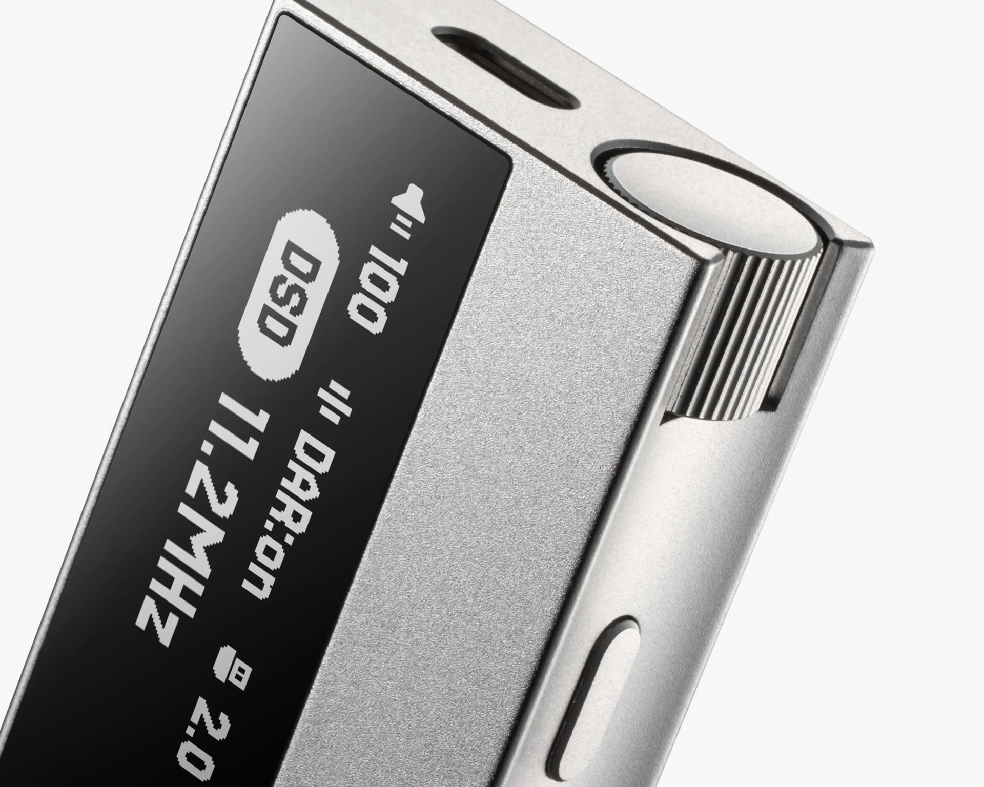 Close-up of a silver digital audio player with a black screen displaying frequency and volume information.