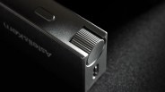 Close-up of a black Astel & Kern device with a textured volume knob and a small button on a dark surface.