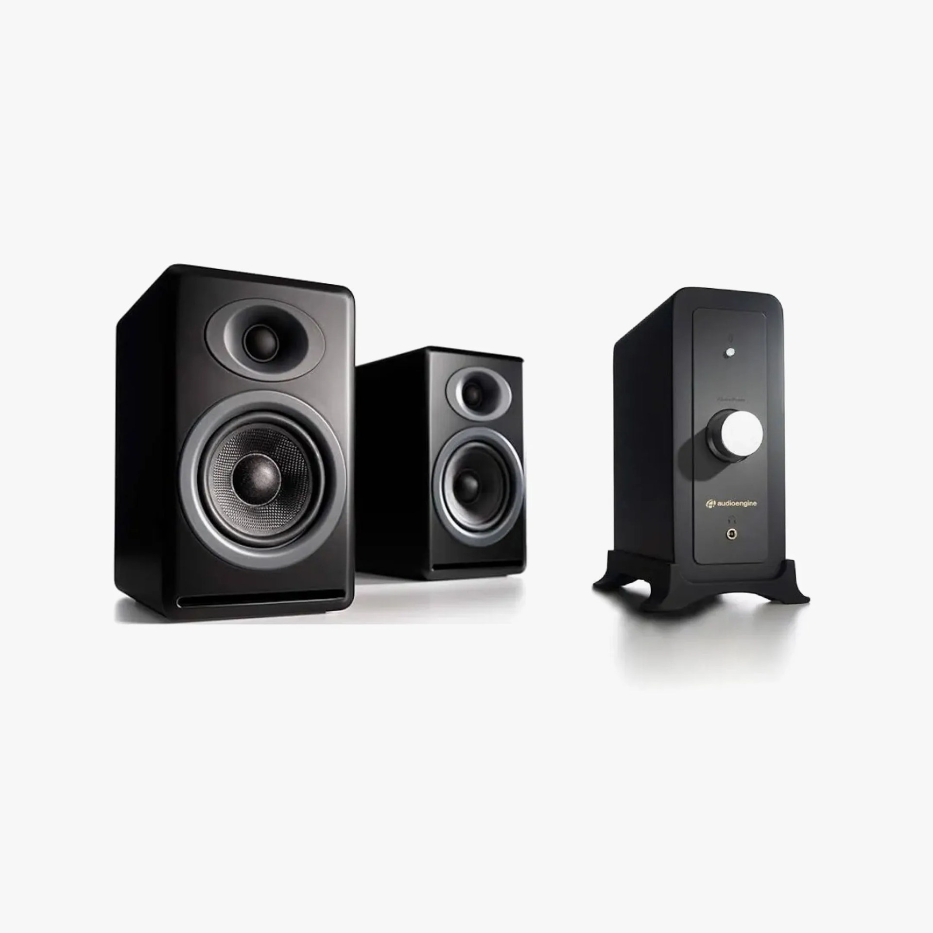 Two black bookshelf speakers and a black amplifier with a large silver volume knob on a white background.