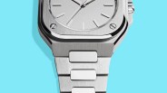 Close-up of a silver stainless steel watch with a brushed metal bracelet on a light blue background.