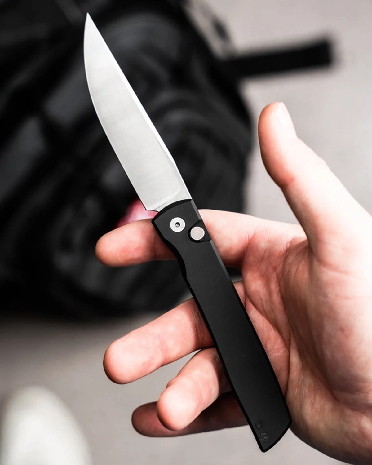 Hand holding a sleek folding knife with a black handle and a sharp silver blade.