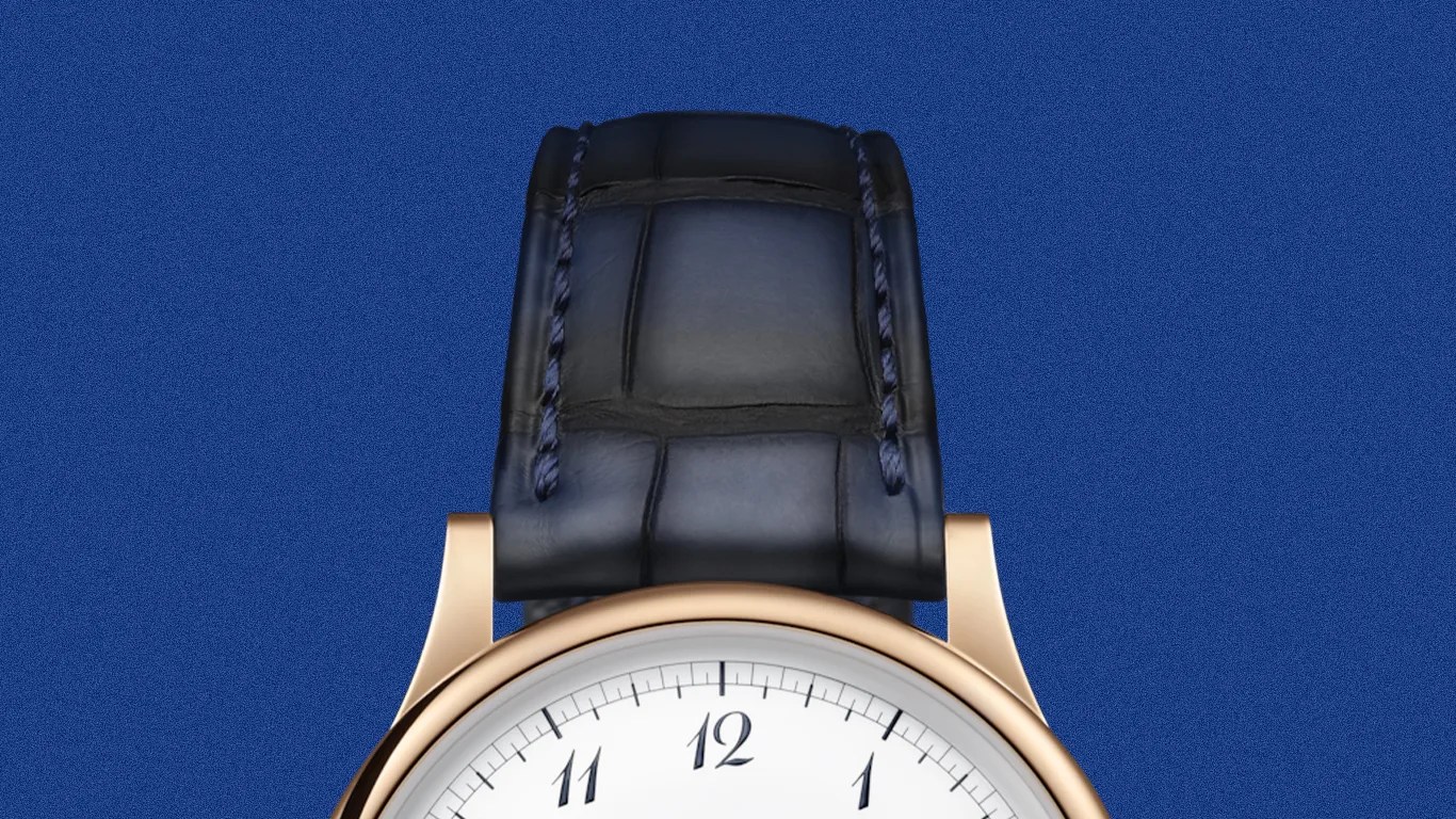 Rose gold watch with white dial and black leather strap on a blue background.