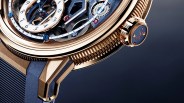 Close-up of a luxury rose gold watch with visible gears, blue accents, and a blue strap.