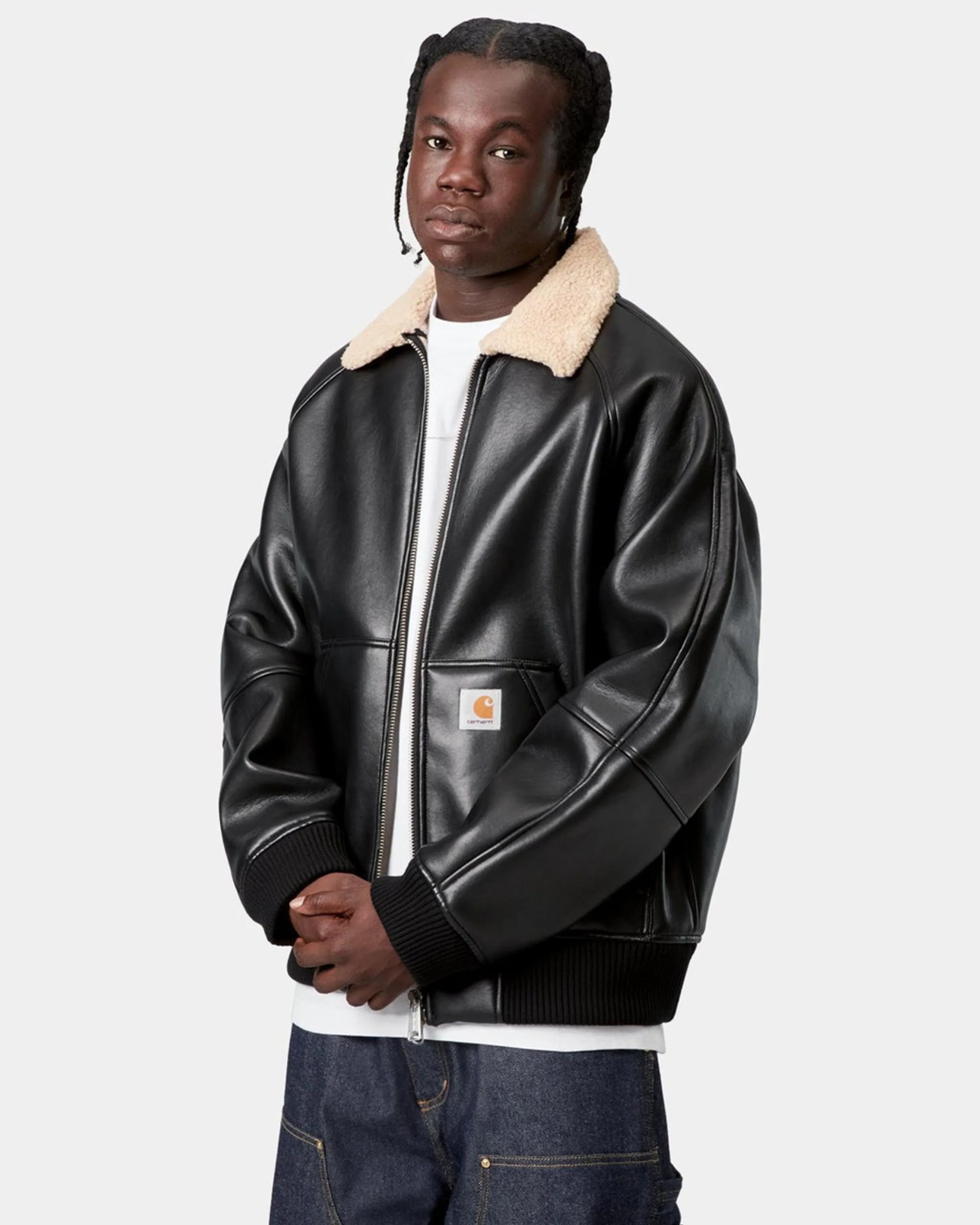 Black leather bomber jacket with beige shearling collar and front patch pocket worn by a person.