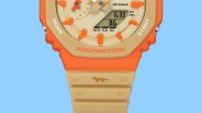 Close-up of an orange and beige watch face with digital and analog displays and a small fox icon on the beige strap.