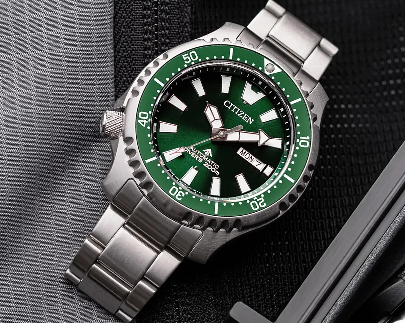 Stainless steel Citizen diver's watch with green bezel and dial, white markers, and day-date display.