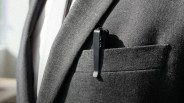 Black metal pen clipped to the pocket of a gray textured blazer worn over a white shirt.