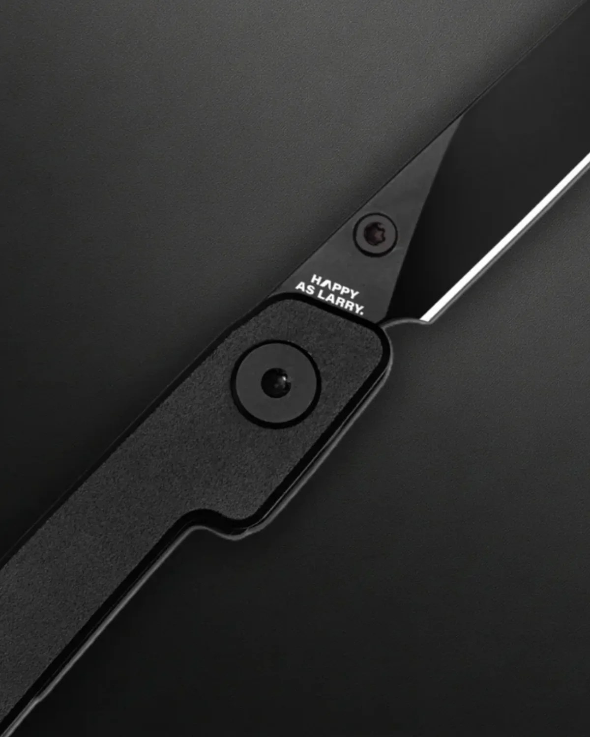 Black folding knife with textured handle and "HAPPY AS LARRY." text near the blade pivot.
