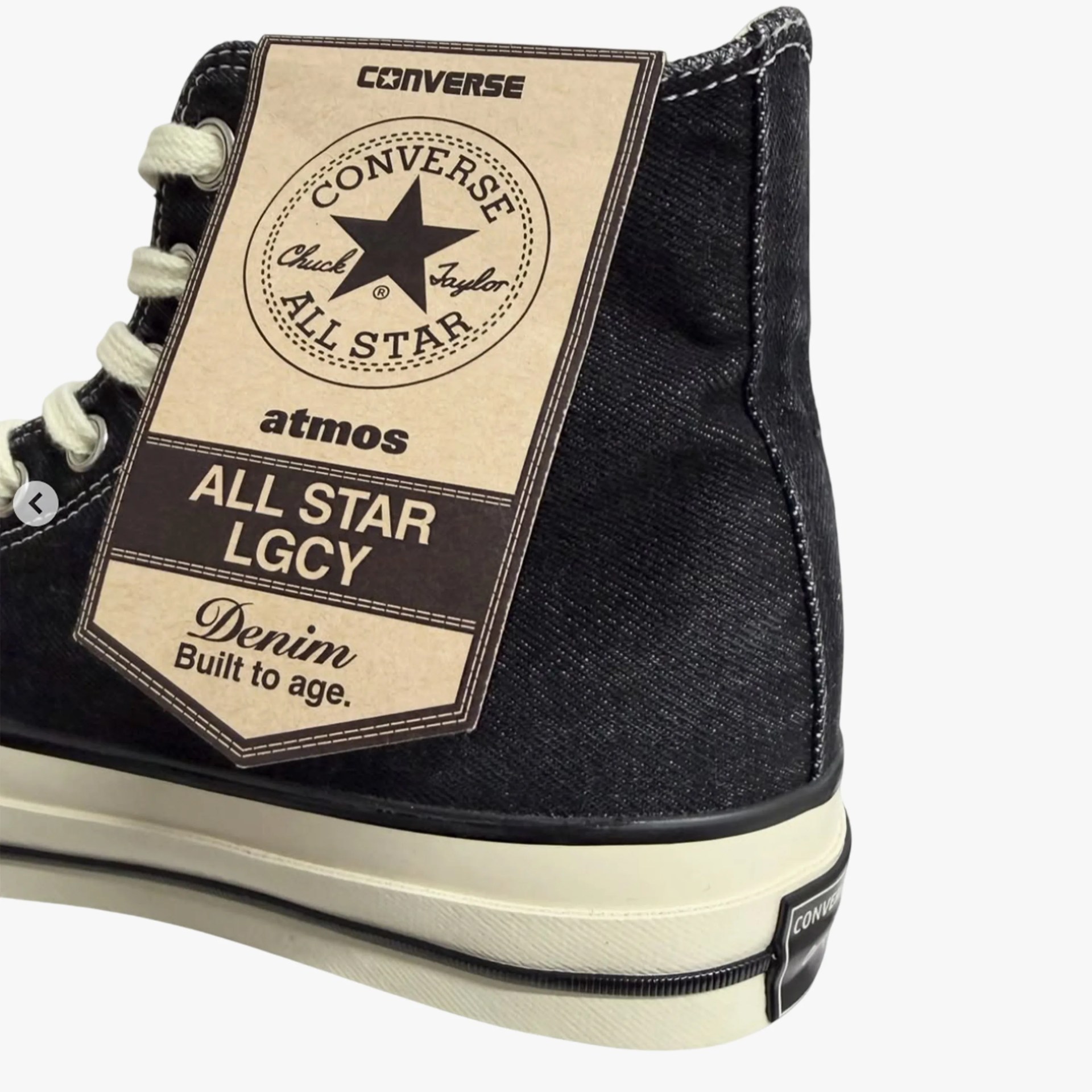 Black denim Converse All Star high-top sneaker with white sole and attached product tag.
