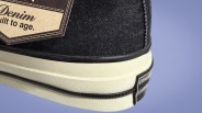 Close-up of the heel of a black denim Converse sneaker with a white sole and a partial label.