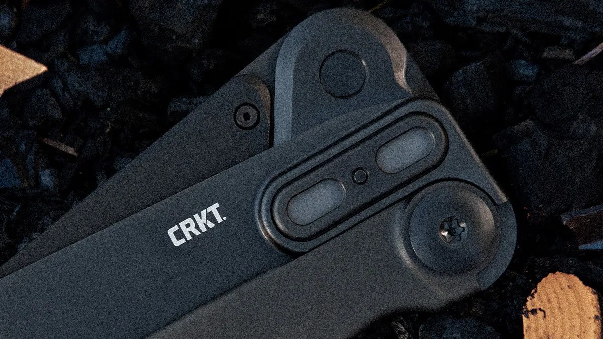 Close-up of a black CRKT folding knife handle with visible pivot screw and locking mechanism.