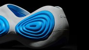 Close-up of a gray and blue Crocs shoe with textured, layered blue accents on the side.
