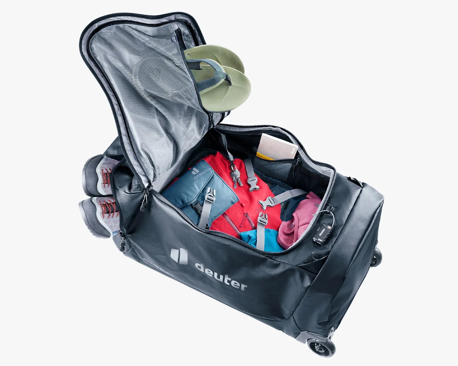 Black Deuter wheeled duffel bag open with packed clothes, shoes in side compartment, and a green neck pillow.