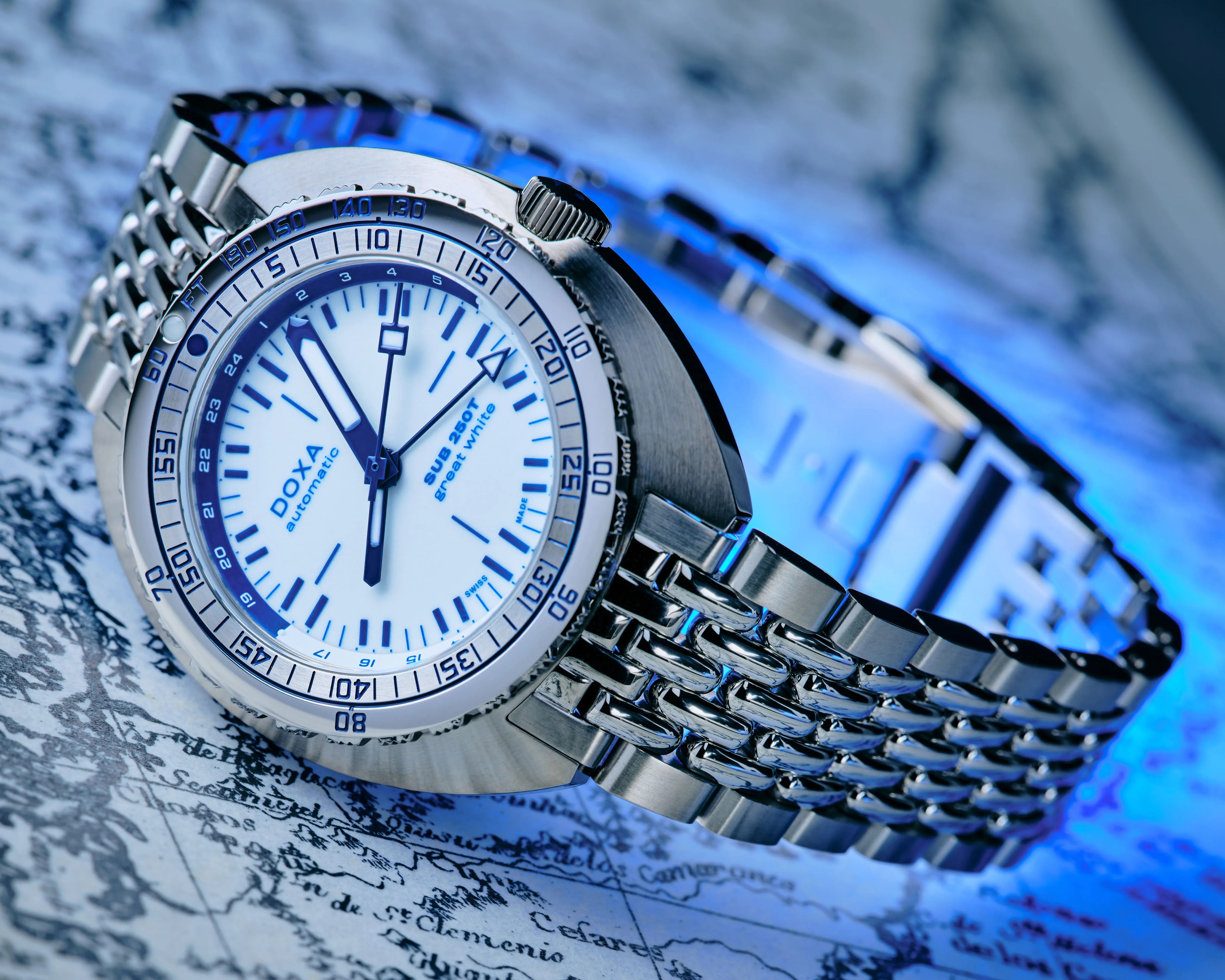 Silver metal bracelet watch with white dial and blue markings on a vintage map background.