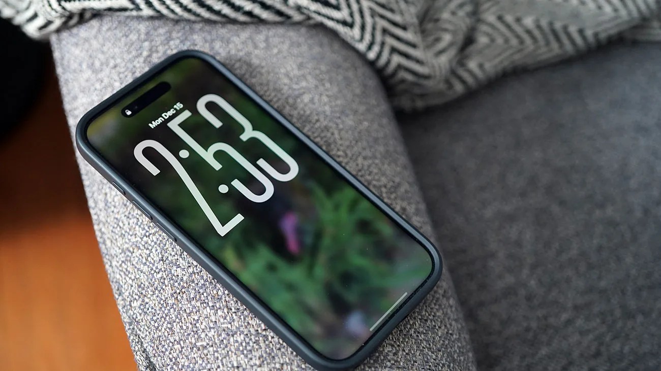 Smartphone with a black case displaying the time 2:53 on a gray fabric surface.