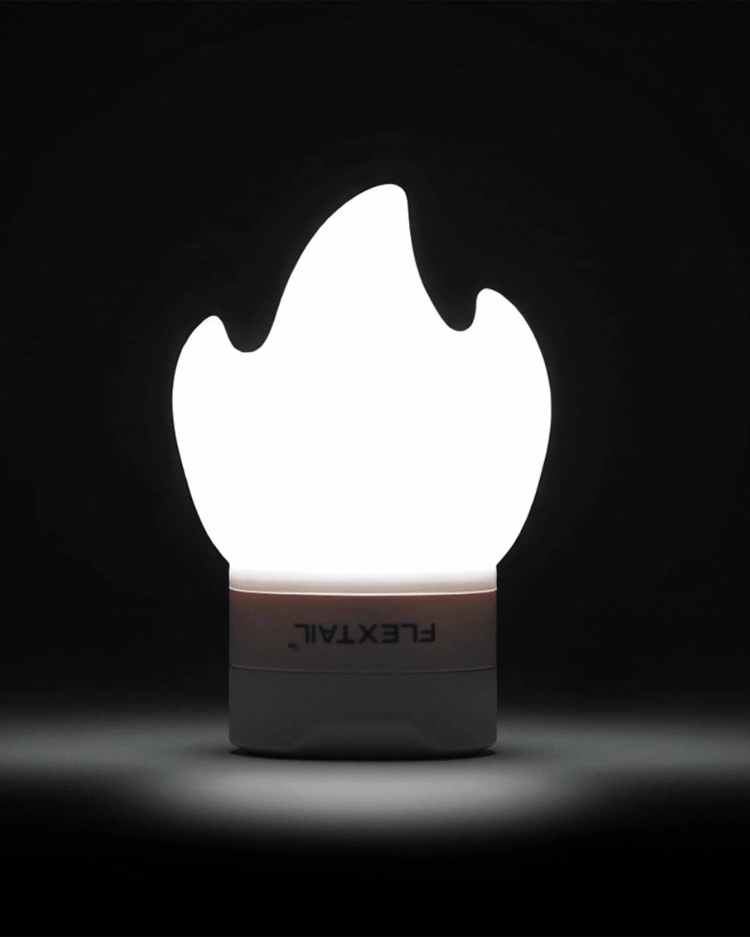 White flame-shaped light with a white base labeled "FLEXTAIL" glowing in a dark setting.