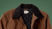 Brown suede jacket with black quilted lining and black corduroy collar, partially unzipped.
