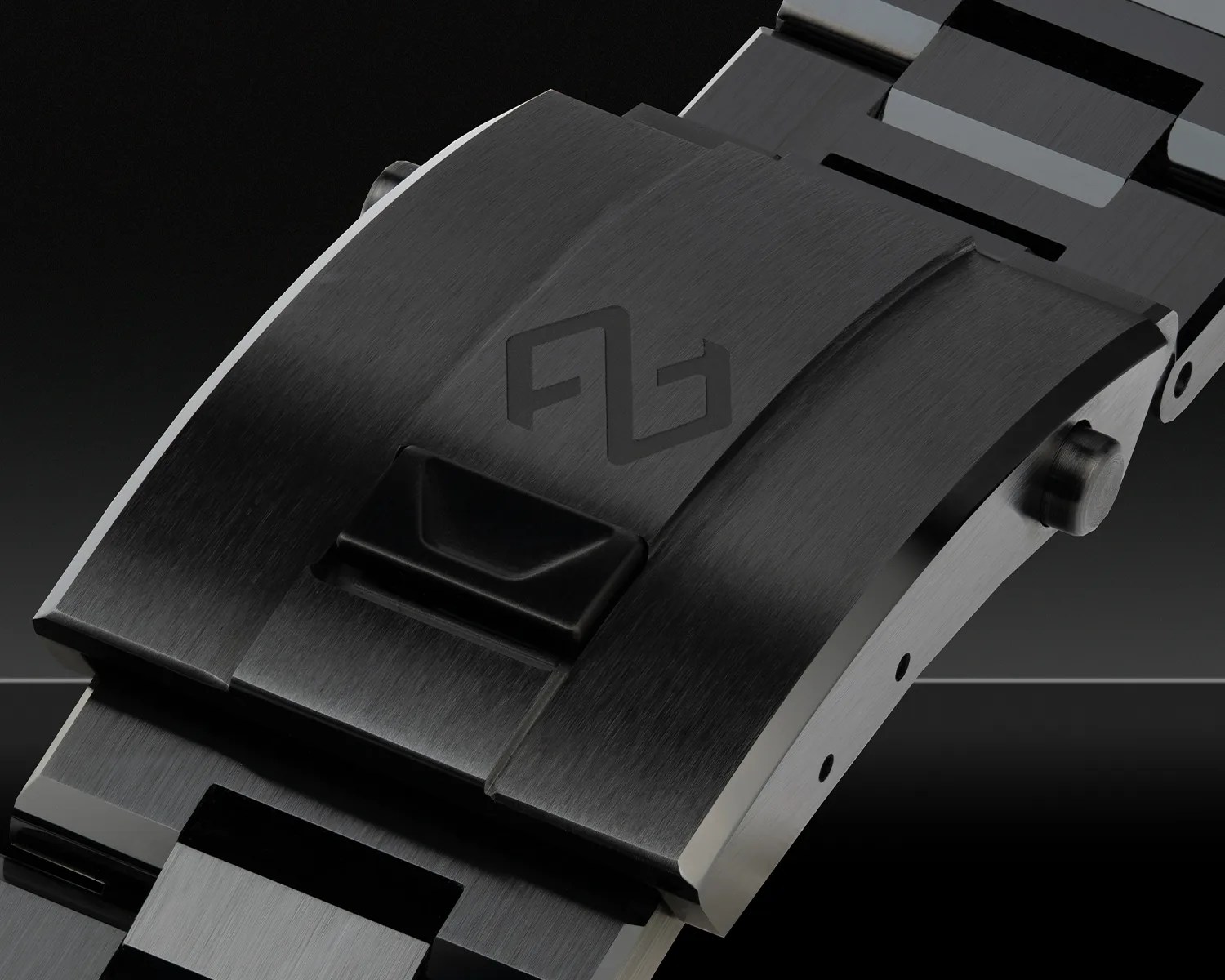 Close-up of a black watch clasp with a push-button release and a subtle logo on top.