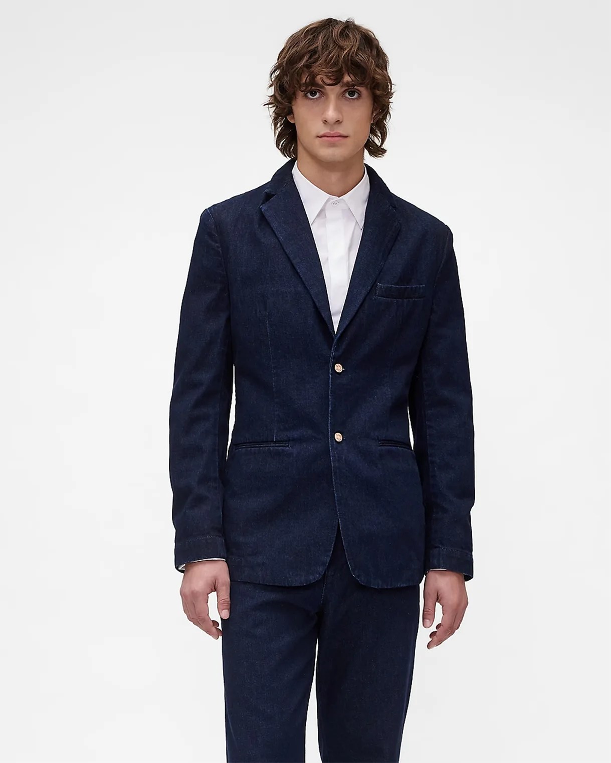 Man wearing a dark blue denim blazer with two buttons over a white dress shirt.