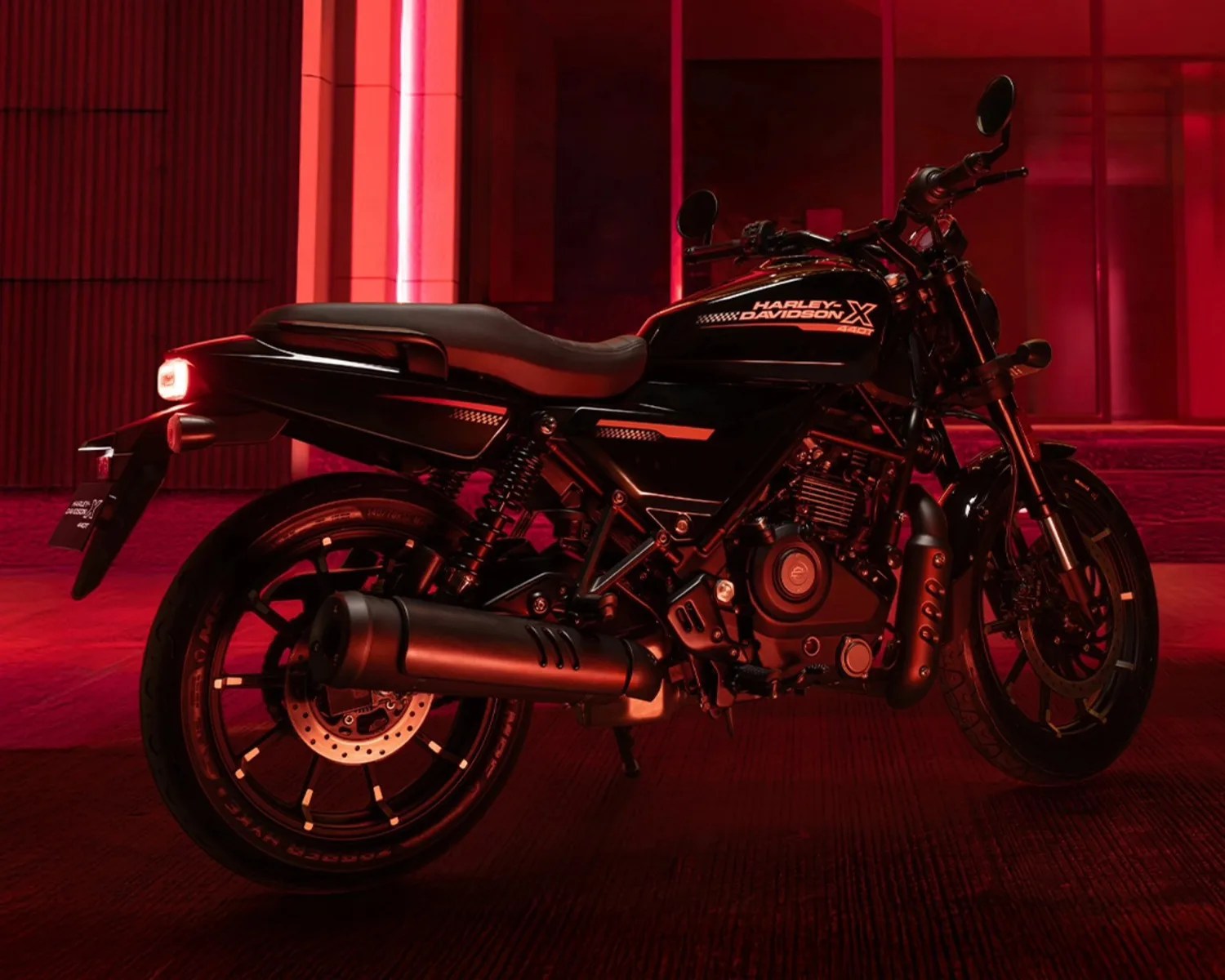 Black Harley-Davidson X 440T motorcycle with red lighting in an urban setting.