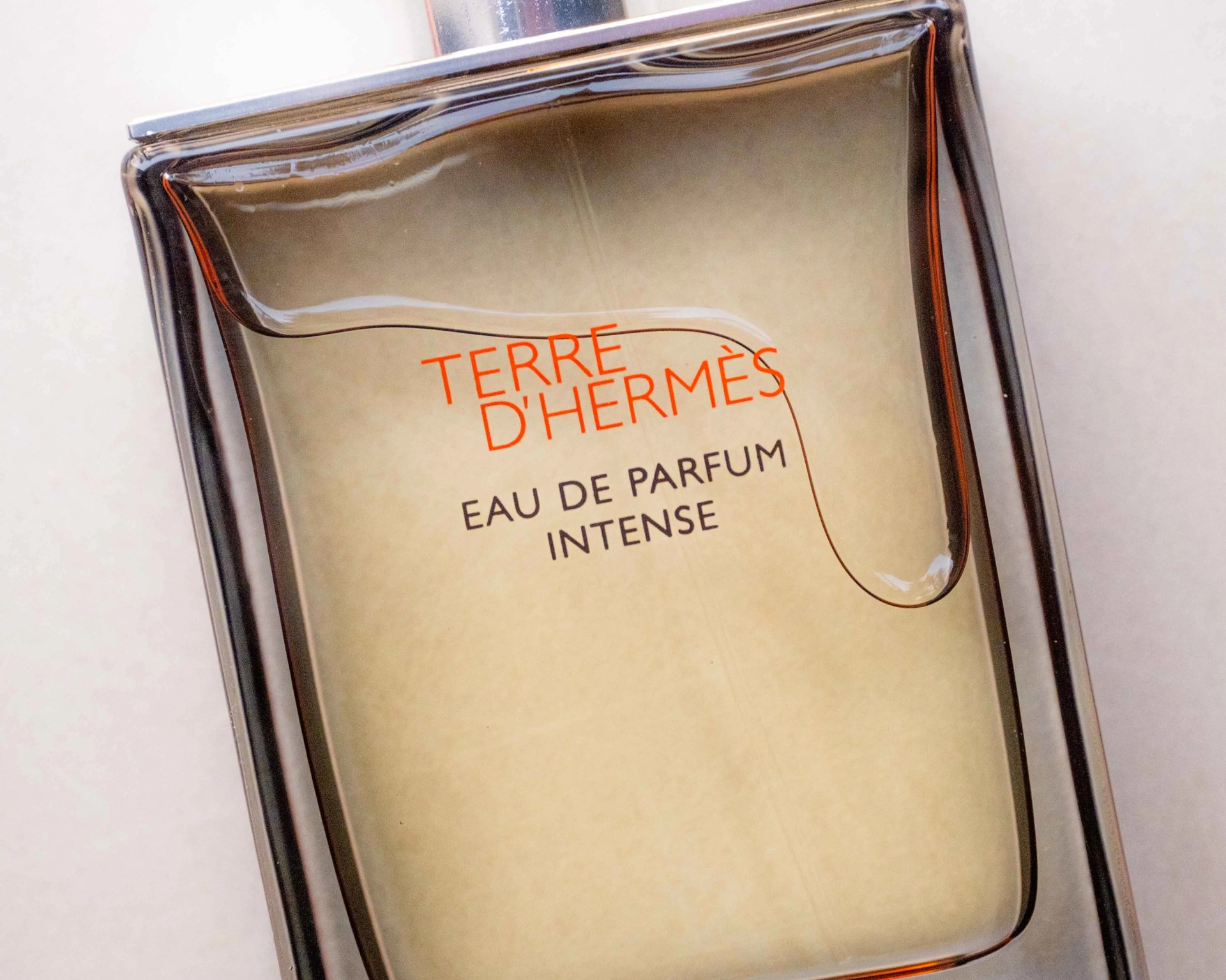 Close-up of a Terre d'Hermès Eau de Parfum Intense bottle with amber-colored liquid inside.