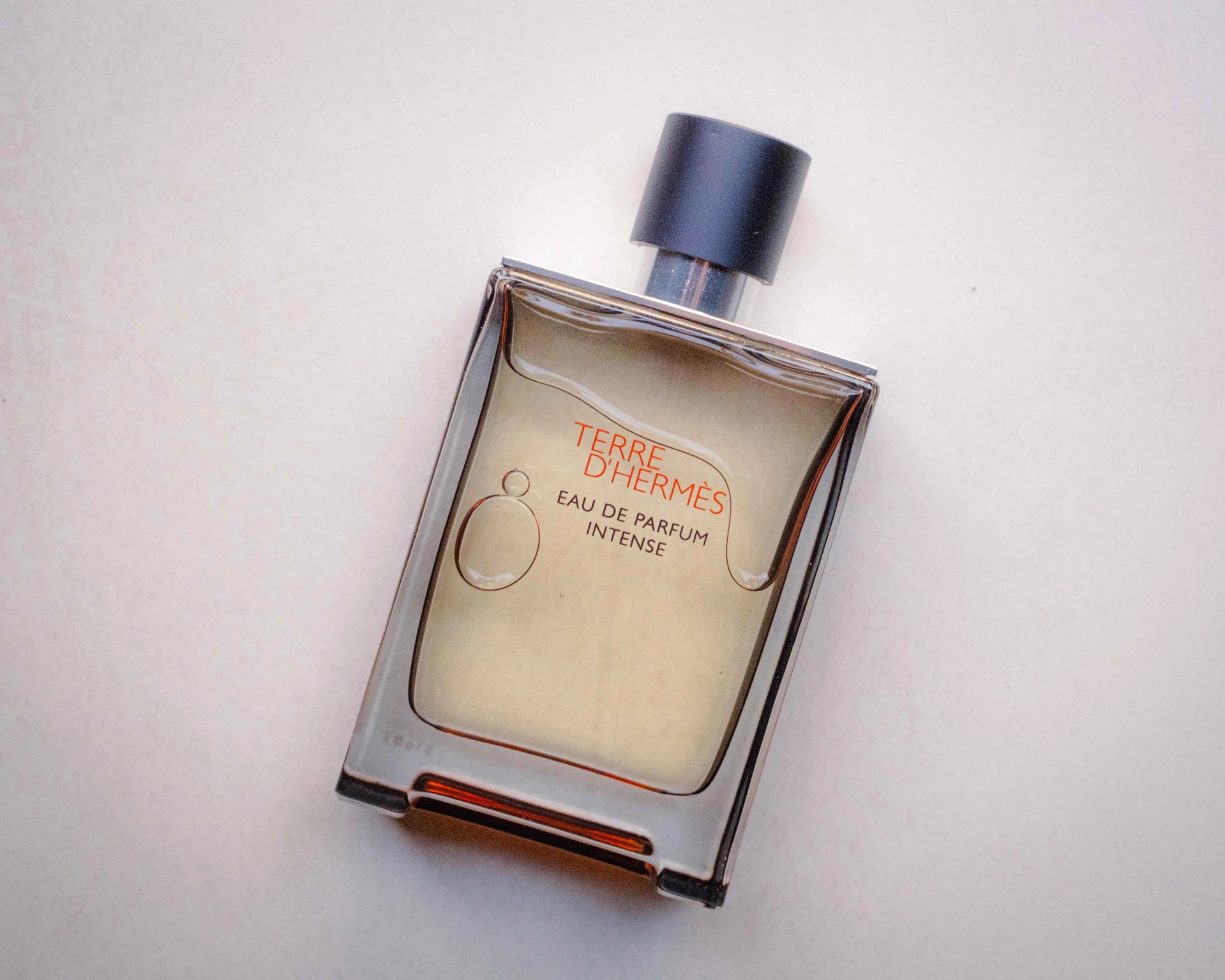 Rectangular glass bottle of Terre d'Hermès Eau de Parfum Intense with black cap on a light surface.