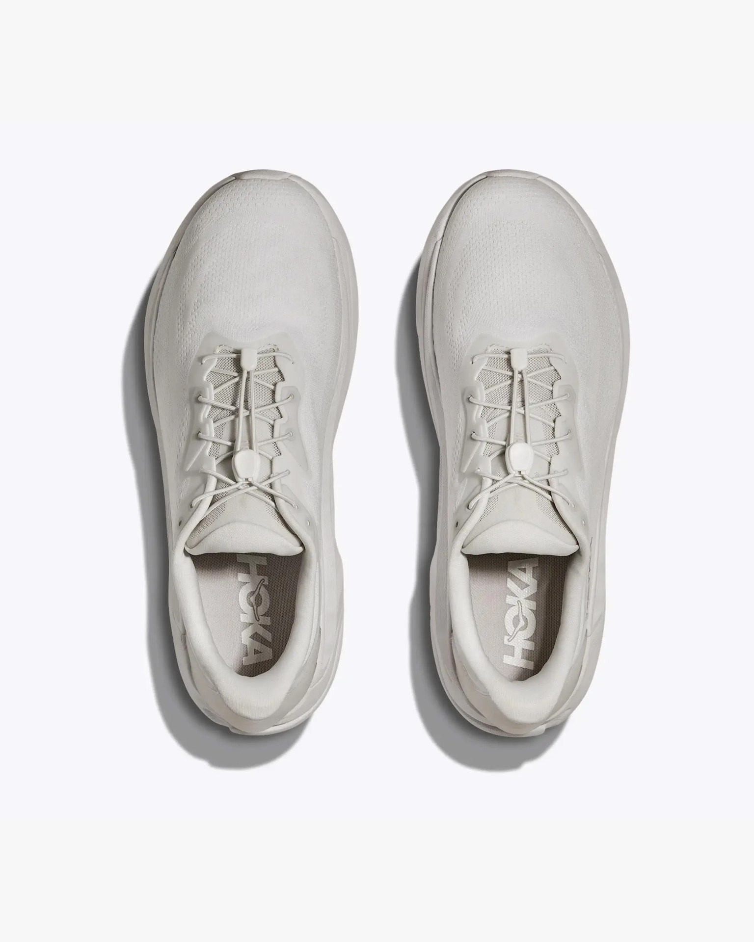Pair of light gray HOKA running shoes with elastic no-tie laces viewed from above.