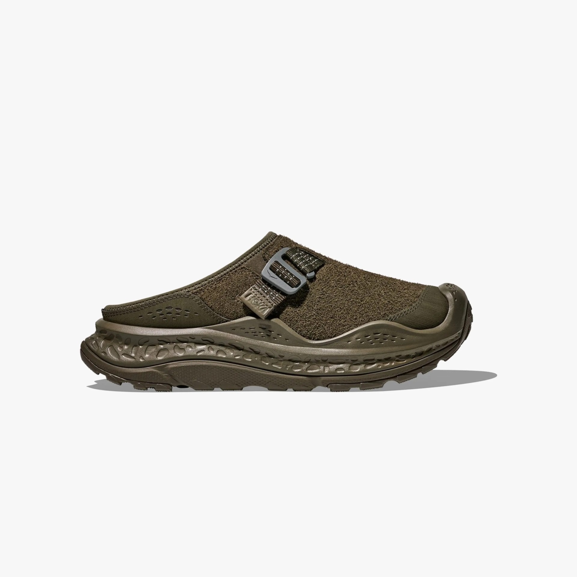 Olive green slip-on shoe with textured upper, adjustable strap, and patterned sole.