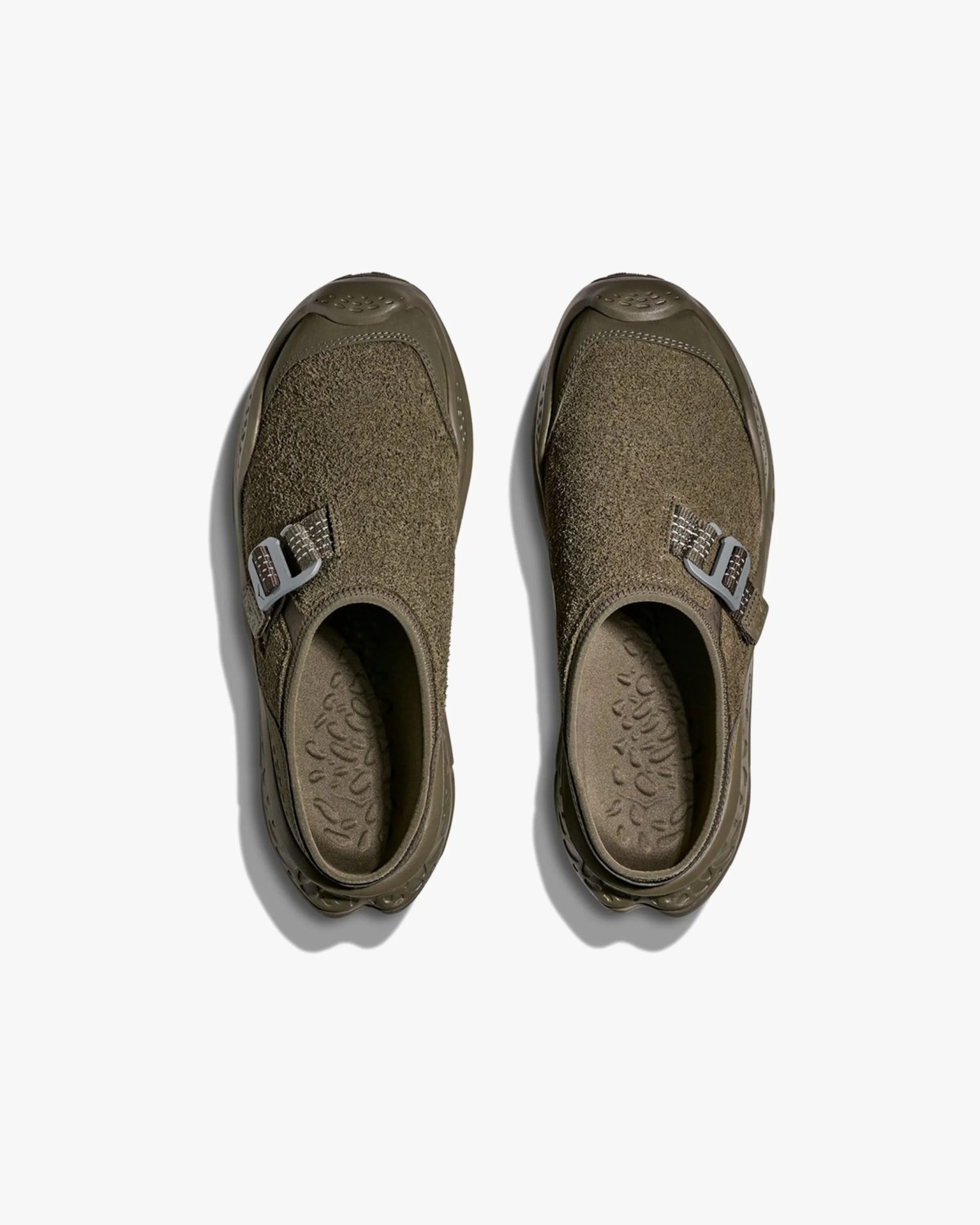 Pair of olive green slip-on shoes with textured fabric uppers and adjustable side buckles, viewed from above.