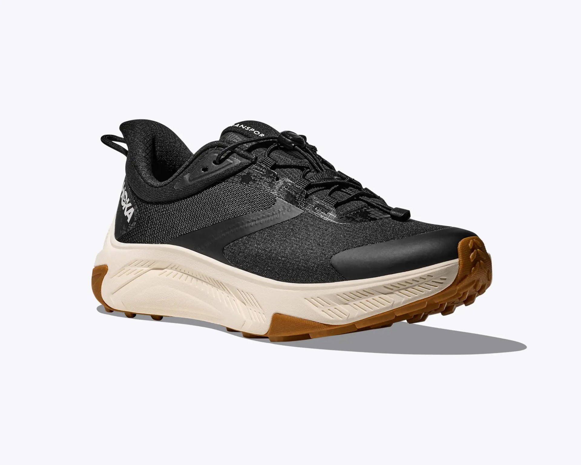 Black and beige trail running shoe with brown rubber sole and quick-lace system.