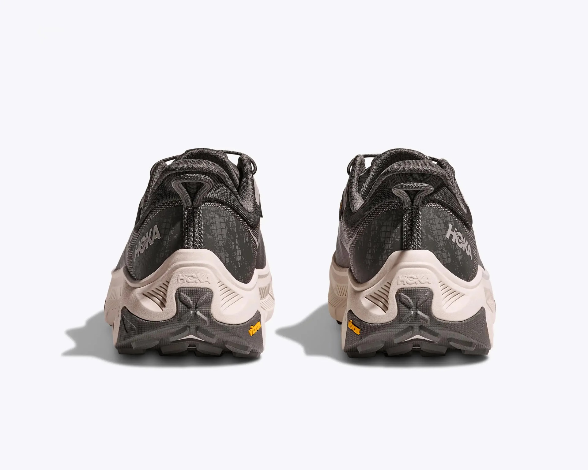 Pair of black and beige Hoka running shoes shown from the back on a white background.