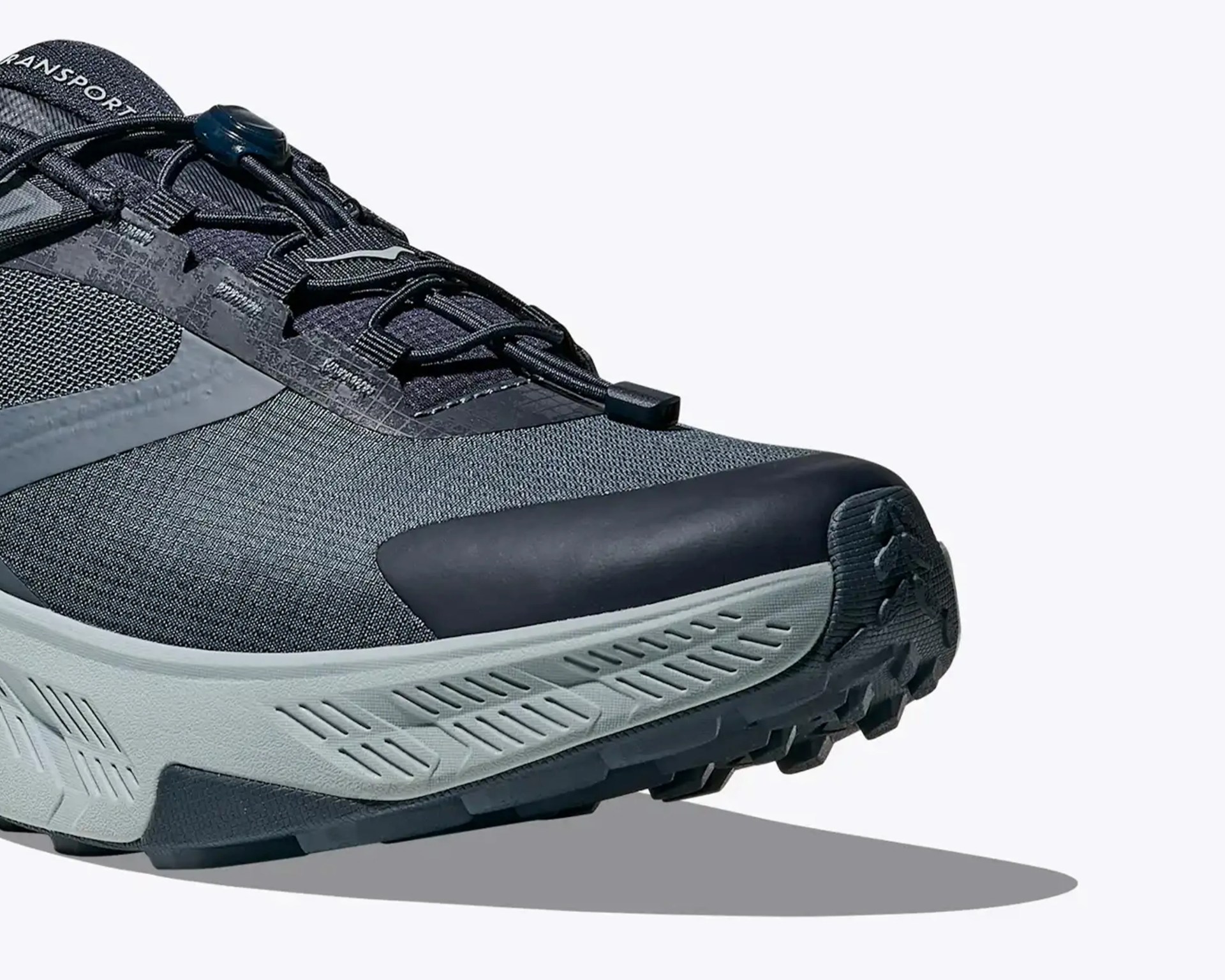 Close-up of a gray and black trail running shoe with textured sole and quick-lace system.