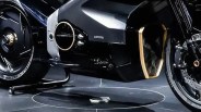 Close-up of a black motorcycle's midsection showing a gold-trimmed air intake and rear wheel with disc brake.