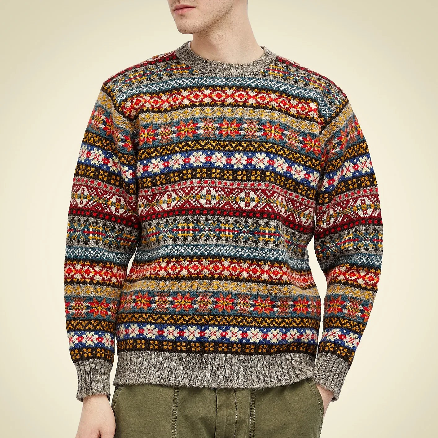 Multicolored patterned knit sweater with ribbed cuffs and hem worn with olive green pants.
