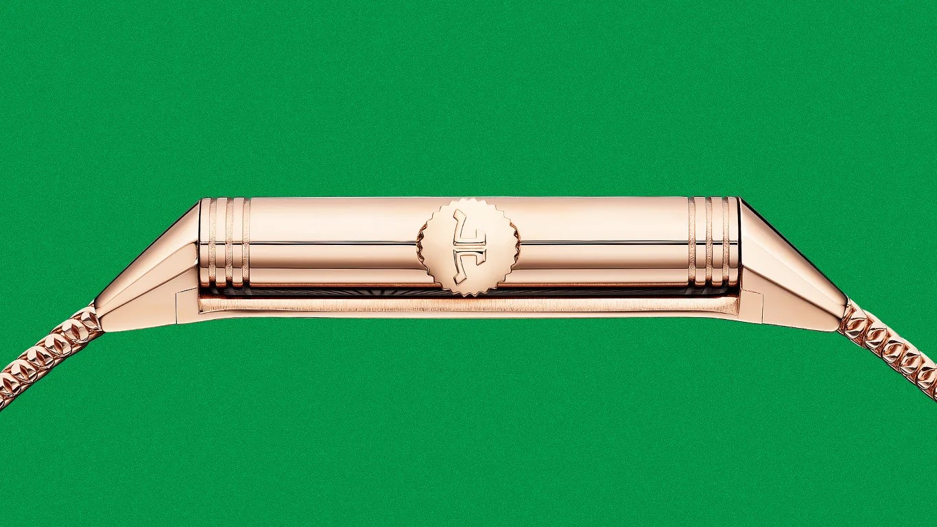 Side view of a rose gold wristwatch case with a ridged crown and linked bracelet against a green background.