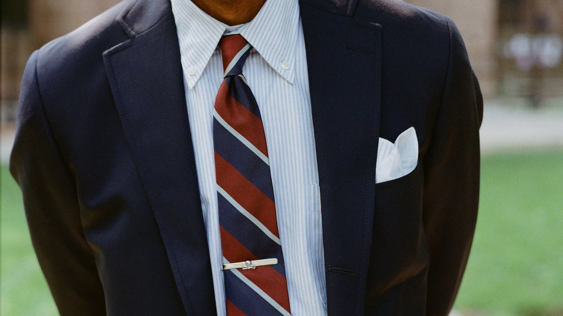Navy blazer over light blue striped dress shirt with red and navy striped tie and white pocket square.