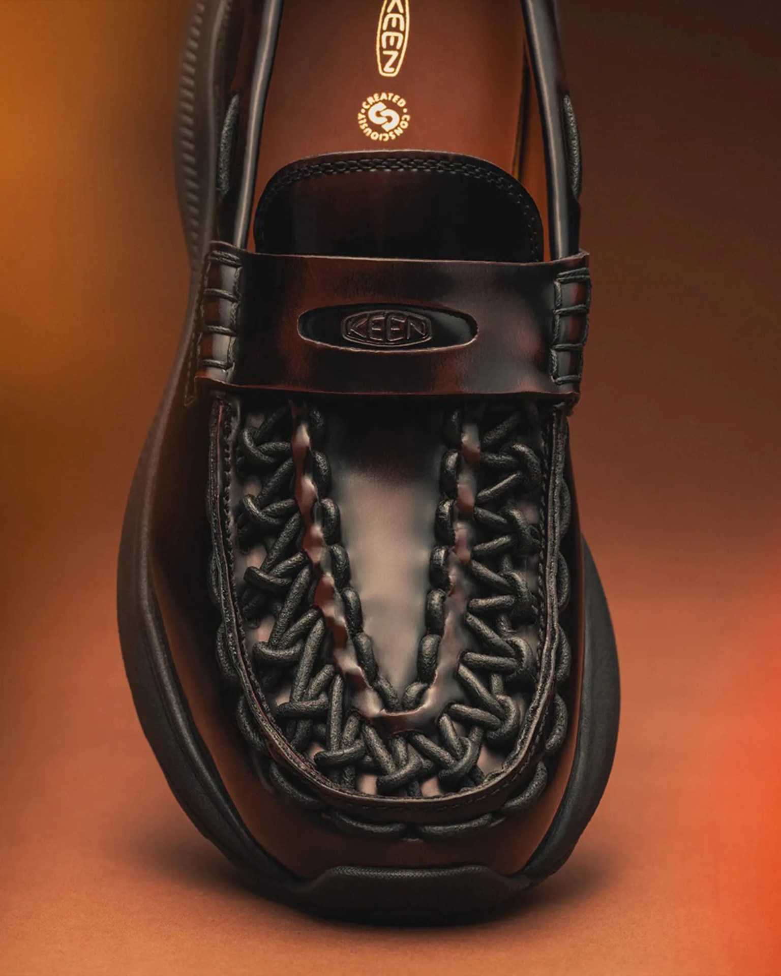 Close-up of a black woven leather KEEN sandal with a braided design and branded strap.