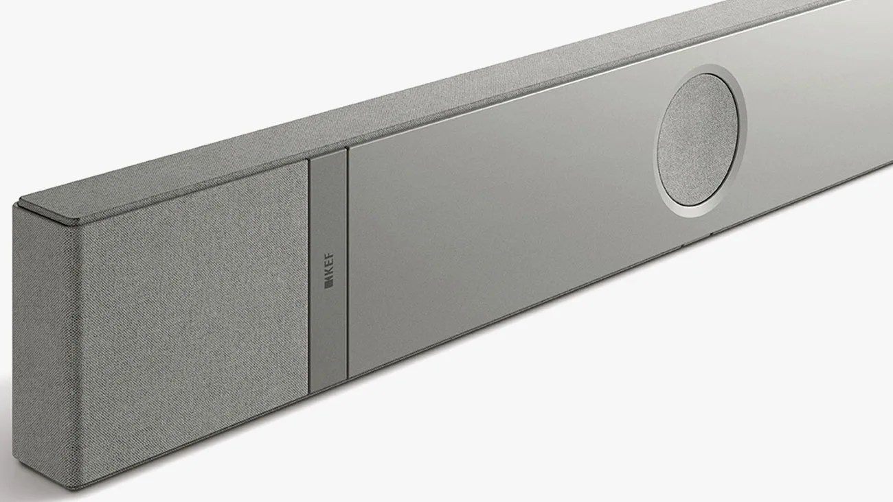 Gray KEF soundbar with fabric-covered speakers and a circular speaker grille on a white background.