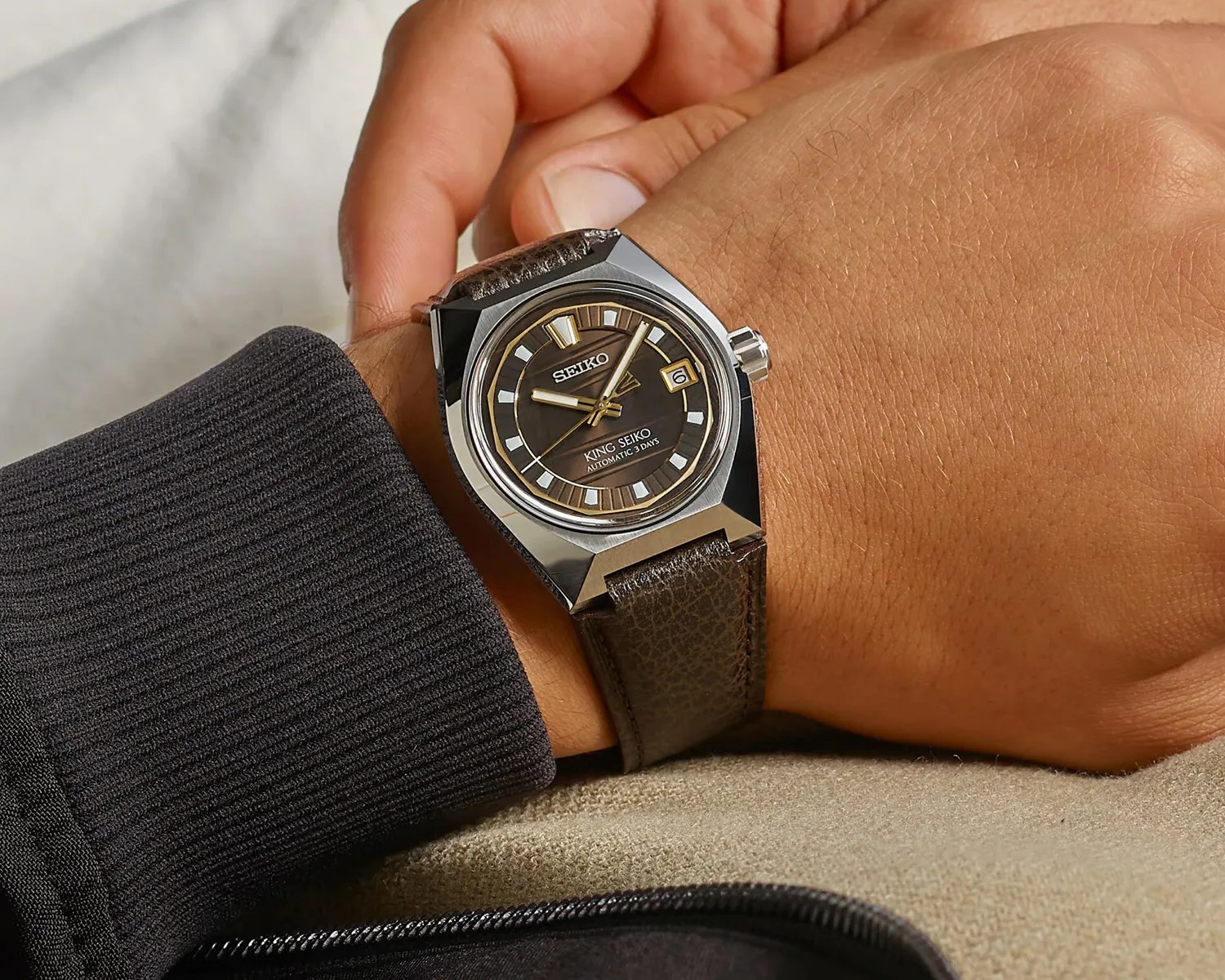 Silver-toned King Seiko watch with brown dial and leather strap worn on a wrist.