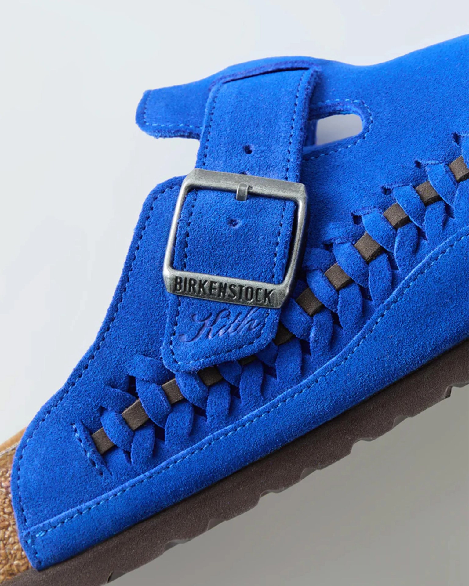Blue suede Birkenstock sandal with woven detailing and metal buckle.