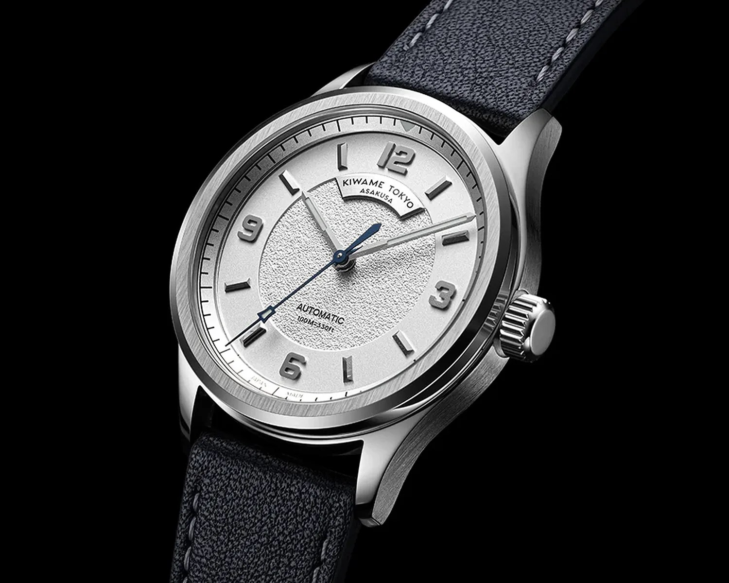 Silver automatic wristwatch with textured white dial, raised numerals, and black leather strap.