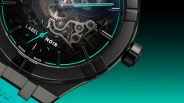 Close-up of a black mechanical watch face with turquoise accents and a turquoise strap.