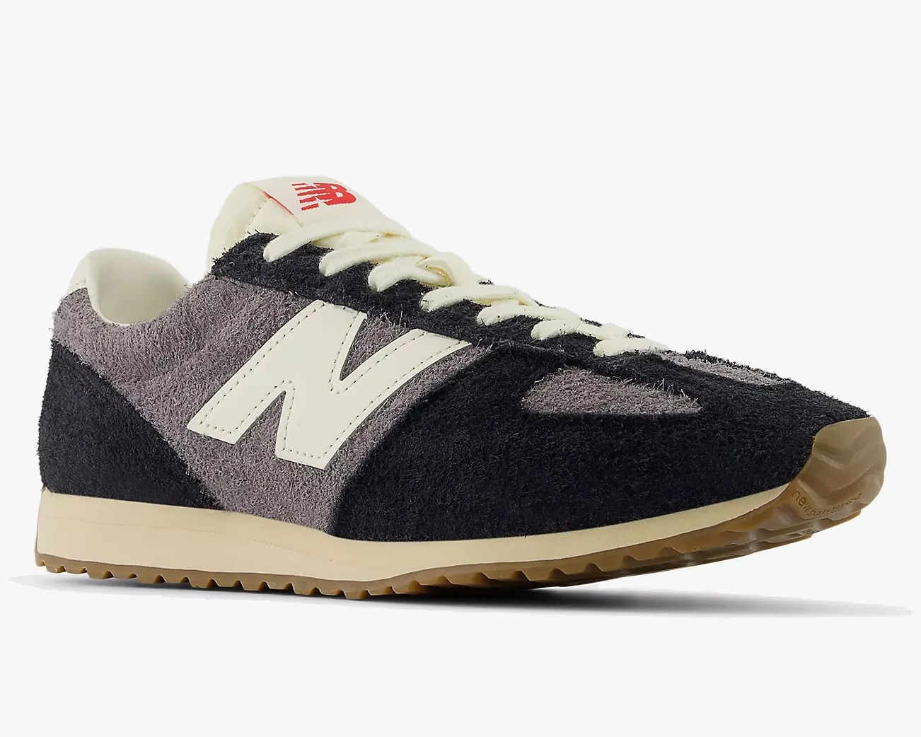 Black and gray suede New Balance sneaker with cream laces and gum sole.