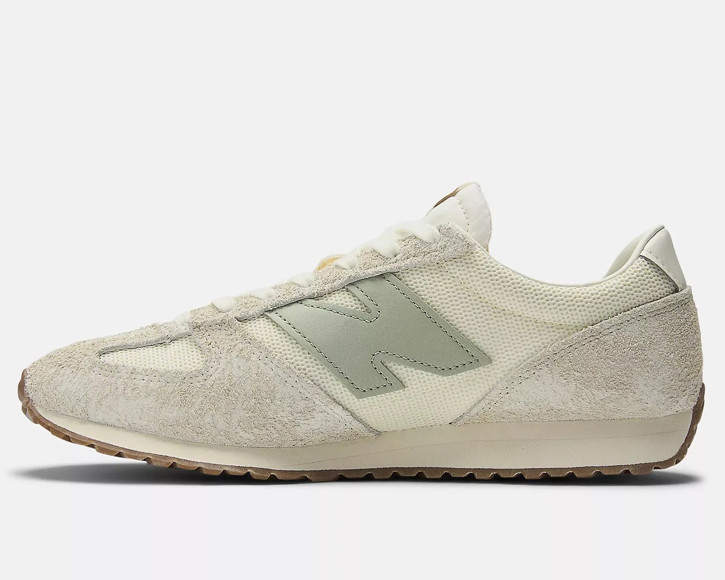 Off-white and light gray suede and mesh New Balance sneaker with gum sole, side view.