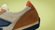 Close-up of a beige mesh and brown suede sneaker heel with an orange suede accent and blue sole.