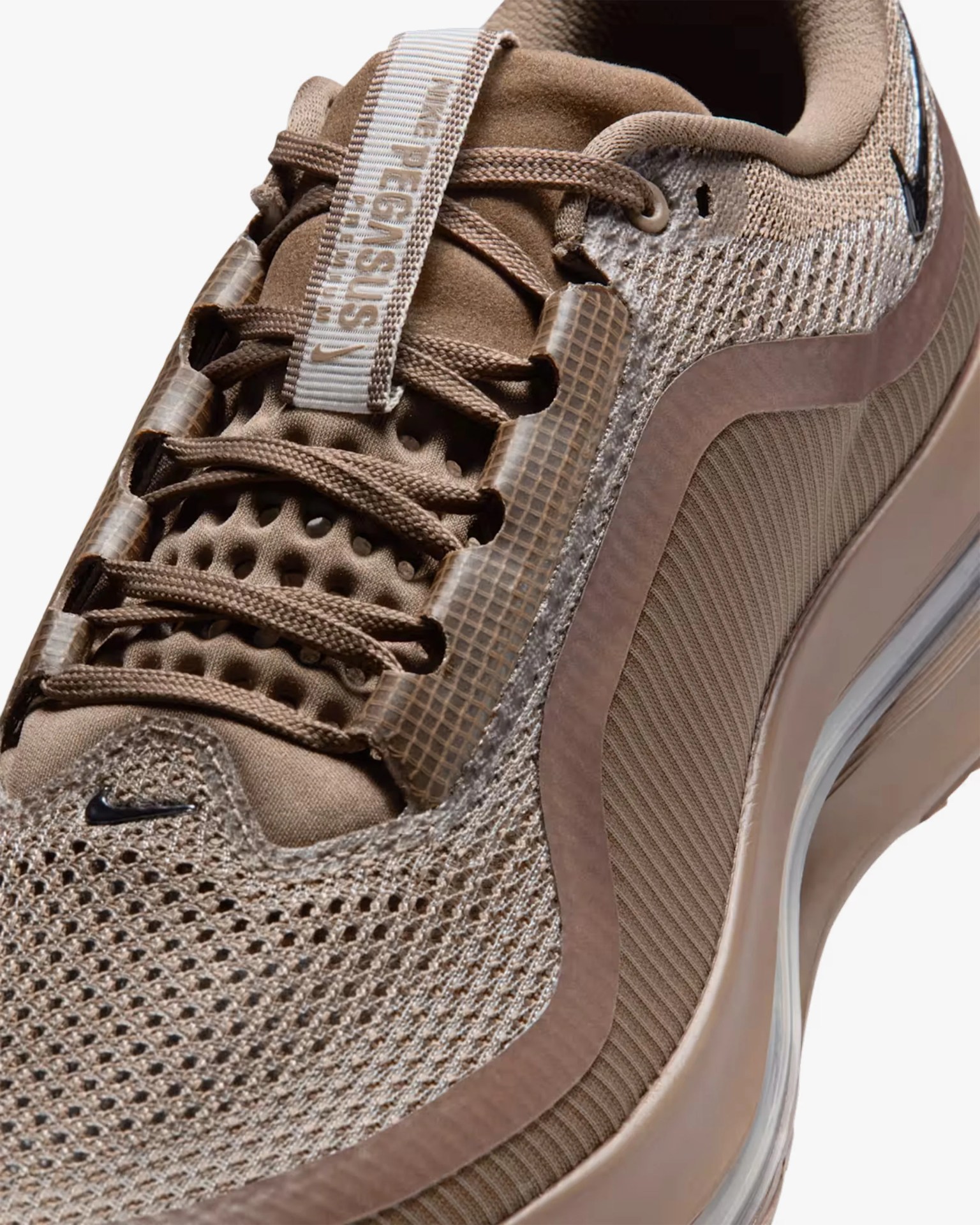 Close-up of a brown Nike sneaker with mesh upper, textured overlays, and visible air cushioning in the sole.